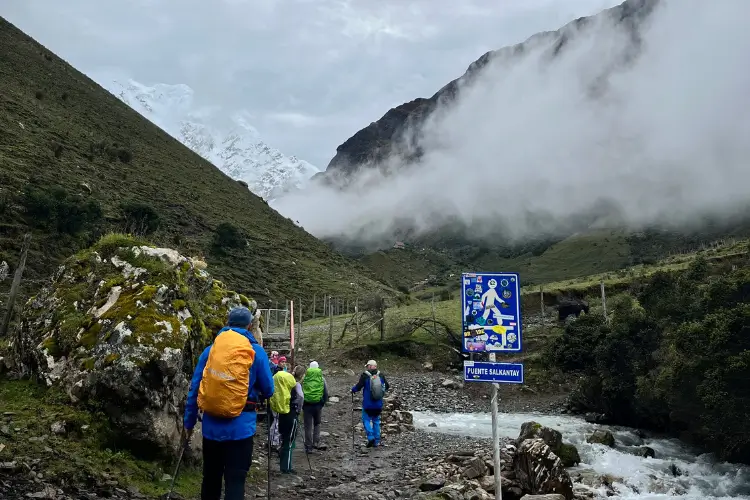 Hikers walking through Salkantaypampa valley surrounded by Andean mountains on the Salkantay Trek
