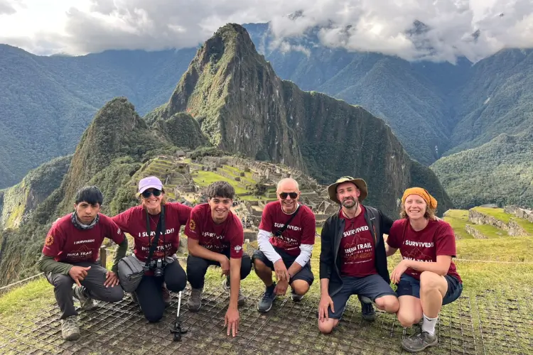 Travelers posing for a panoramic photo with the iconic Machu Picchu citadel in the background